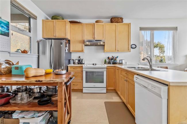 Kitchen featuring a sink, under cabinet range hood, white appliances, and light brown cabinetry | Image 8