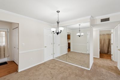 Dining room close up with wall of mirrors. Hall to bedrooms showing hall bath. Hall bath has a private entrance from second bedroom. On the left, door to patio and doors to utility closet. | Image 3