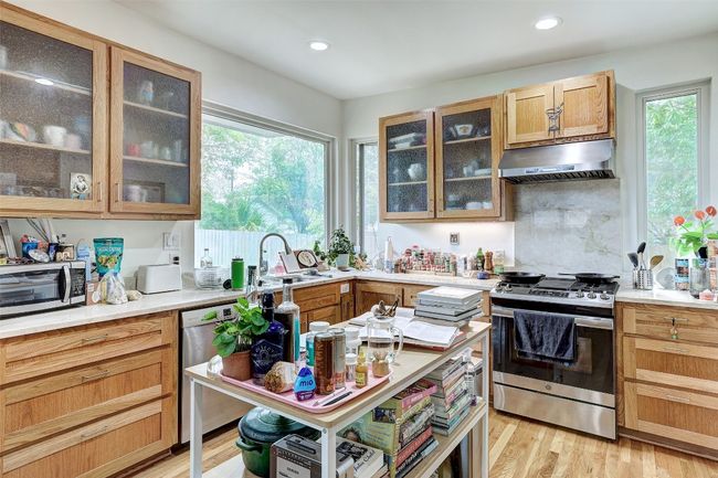 Kitchen featuring under cabinet range hood, stainless steel appliances, light countertops, and a sink | Image 31