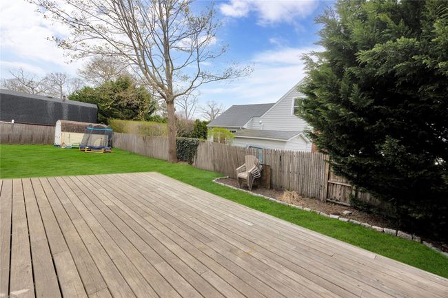 Deck featuring a fenced backyard, an outdoor structure, a storage shed, and a lawn | Image 24