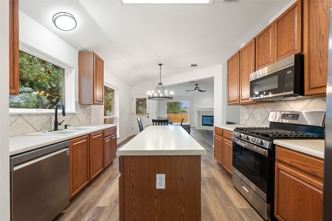 Kitchen with appliances with stainless steel finishes, light wood-type flooring, tasteful backsplash, and vaulted ceiling | Image 23