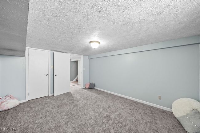 Basement featuring a textured ceiling and carpet flooring | Image 28