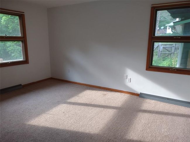 Carpeted spare room featuring baseboard heating and plenty of natural light | Image 12