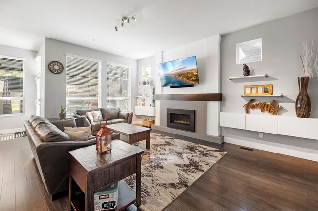 Living room with visible vents, baseboards, wood finished floors, and a fireplace | Image 6