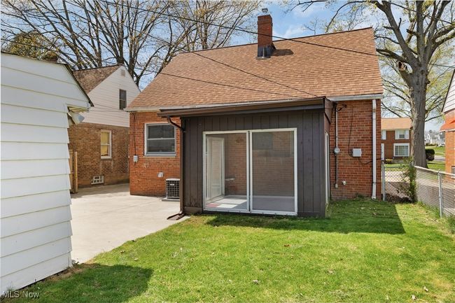 Rear view of property with a chimney, a yard, fence, a shingled roof, and central AC unit | Image 28