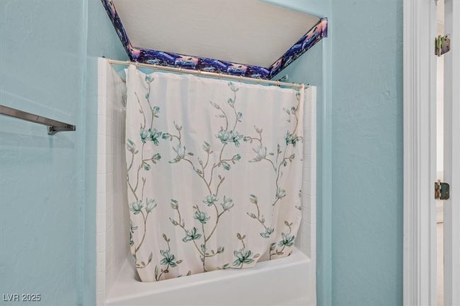 Bathroom featuring shower / bath combination with curtain and a textured wall | Image 17