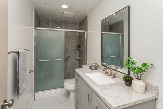 Bathroom featuring a textured ceiling, a stall shower, toilet, vanity, and marble finish floor | Image 26