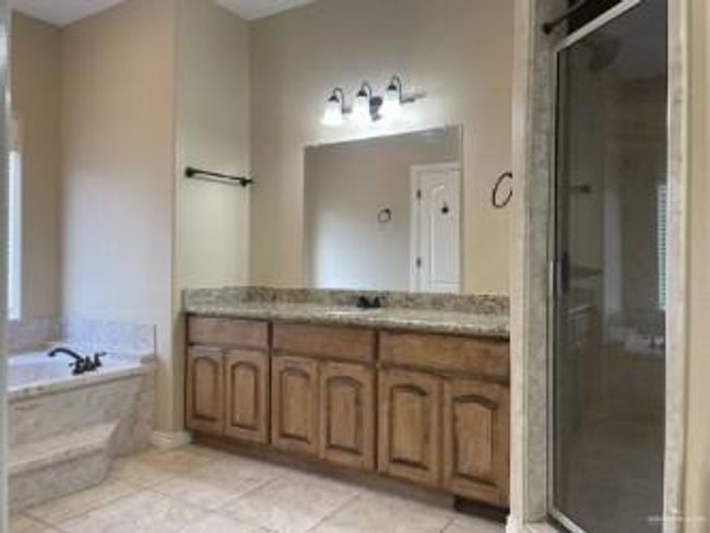 Full bathroom featuring vanity, a shower stall, a garden tub, and tile patterned flooring | Image 5