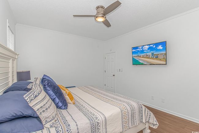 Bedroom featuring wood finished floors, crown molding, ceiling fan, and baseboards | Image 16
