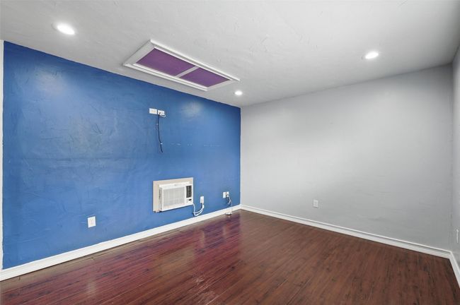 Unfurnished room with wood finished floors, baseboards, recessed lighting, attic access, and an AC wall unit | Image 18