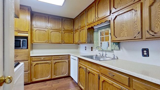 Kitchen featuring a sink, stainless steel microwave, white dishwasher, light wood-style flooring, and light countertops | Image 9