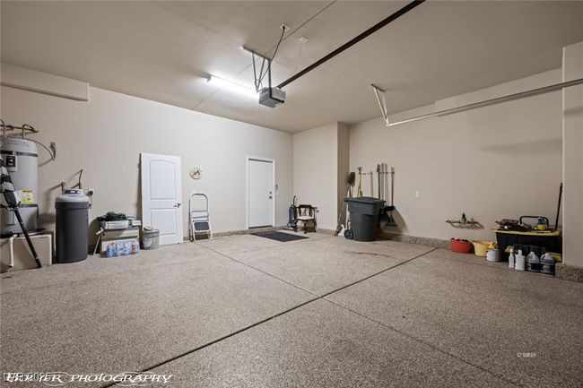 Garage featuring secured water heater and a garage door opener | Image 50