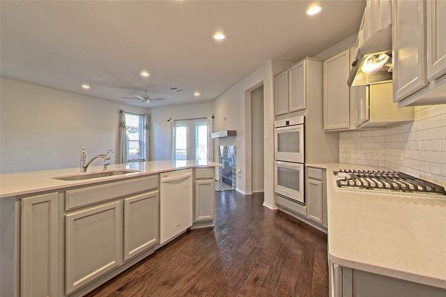 Kitchen featuring white appliances, wall chimney exhaust hood, recessed lighting, backsplash, and ceiling fan | Image 15