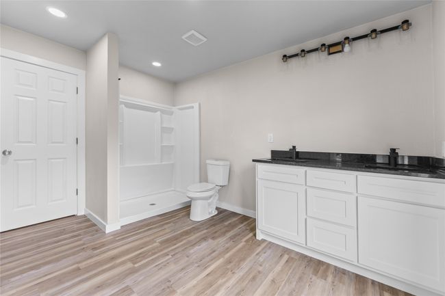 Full bathroom featuring baseboards, wood finished floors, a shower, double vanity, and recessed lighting | Image 10