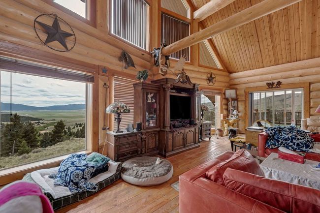 Living room with high vaulted ceiling, log walls, wood-type flooring, wooden ceiling with exposed beams, and a mountain view | Image 25