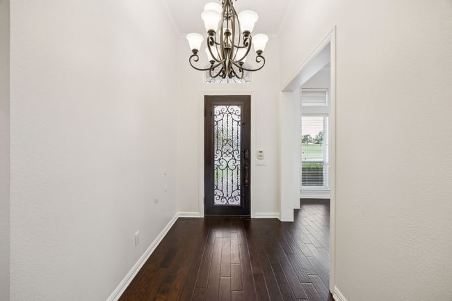 Foyer entrance featuring a wrought iron chandelier, baseboards, and dark wood-type flooring | Image 4