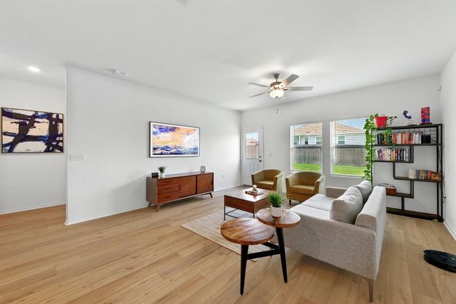 Living room with light wood-style flooring, a ceiling fan, and baseboards | Image 6