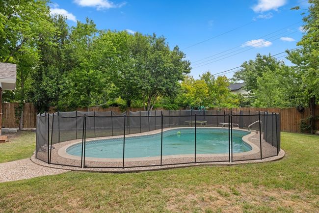 View of swimming pool with a fenced in pool, a lawn, and a fenced backyard | Image 8