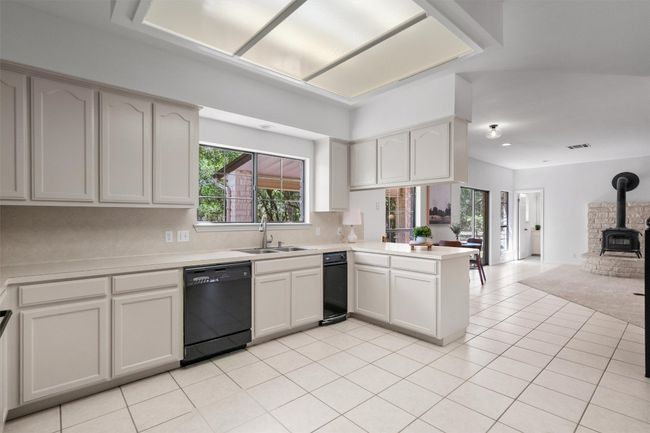 Kitchen with a peninsula, light countertops, a sink, open floor plan, and dishwasher | Image 13