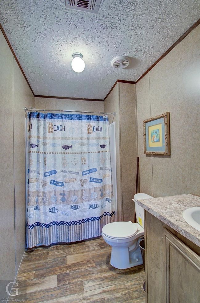 Full bath featuring ornamental molding, wood finished floors, vanity, a textured ceiling, and a shower with shower curtain | Image 7