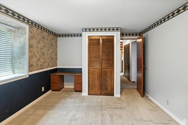 Bedroom featuring built in desk, carpet flooring, a closet, and a wainscoted wall | Image 18