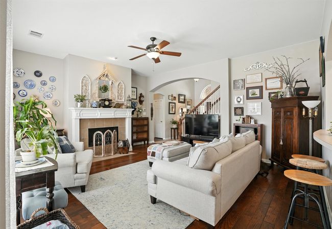 Living room with arched walkways, dark wood-style floors, a ceiling fan, and a tiled fireplace | Image 9