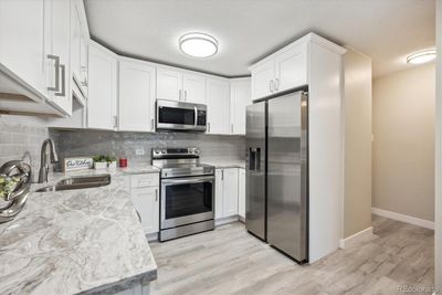 Kitchen features white shaker cabinets, quartz counters and stainless appliances | Image 2