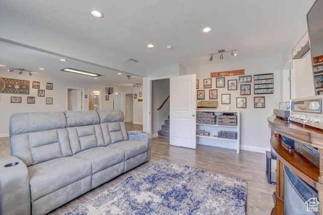 Living room with wood finished floors, baseboards, recessed lighting, and stairs | Image 10