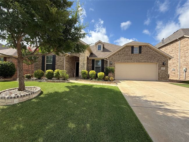 Traditional-style home featuring an attached garage, brick siding, concrete driveway, a front lawn, and roof with shingles | Image 25