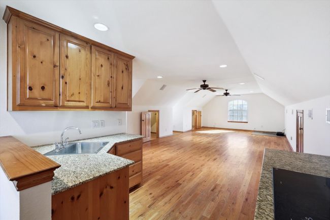 Garage apartment Kitchen featuring a sink, light wood-style floors, lofted ceiling, open floor plan, and brown cabinets | Image 25