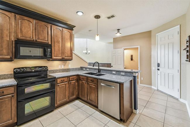 The kitchen boasts 42-inch cabinets with elegant crown molding and granite countertops. | Image 10