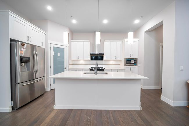 Kitchen with stainless steel appliances, a sink, light countertops, dark wood finished floors, and recessed lighting | Image 12