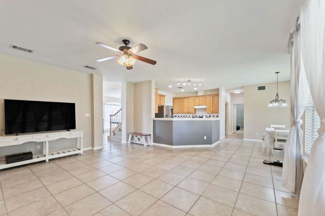 Living room featuring light tile patterned floors, ceiling fan, and stairs | Image 8