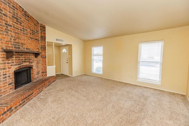 Unfurnished living room featuring carpet flooring, a fireplace, and vaulted ceiling | Image 5