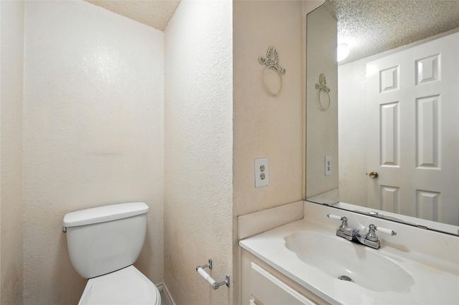 Half bathroom featuring a textured ceiling, vanity, and a textured wall | Image 33