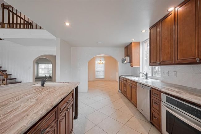 Enjoy plenty of counter space and a deep sink overlooking the backyard. The kitchen opens into the dining area through a beautiful arched entryway, making meal service and flow effortless. | Image 17