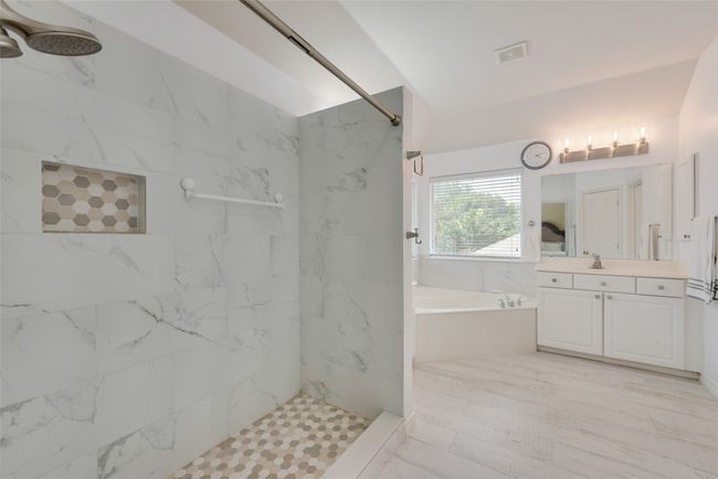 Bathroom with a bath, a marble finish shower, and vanity | Image 19