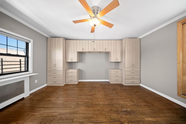 Unfurnished bedroom with baseboards, dark wood-style flooring, ornamental molding, and ceiling fan | Image 24