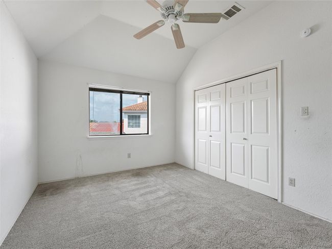 Unfurnished bedroom with vaulted ceiling, carpet flooring, a closet, and a ceiling fan | Image 21