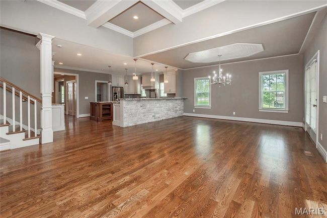 Living room featuring coffered ceiling, ornamental molding, dark wood-type flooring, and a notable chandelier | Image 19
