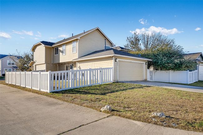 View of property exterior featuring driveway, a garage, and a fenced front yard | Image 20