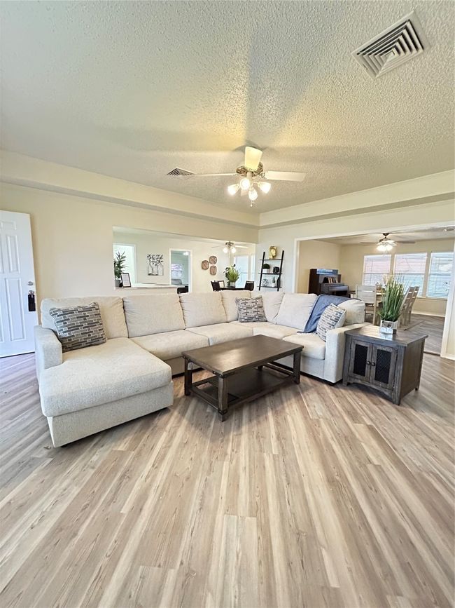 Living area featuring visible vents, light wood-style floors, ceiling fan, and a textured ceiling | Image 8