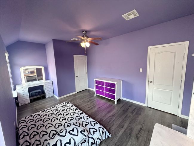 Upstairs bedroom with purple walls, wood finished floors, lofted ceiling, and a ceiling fan | Image 25