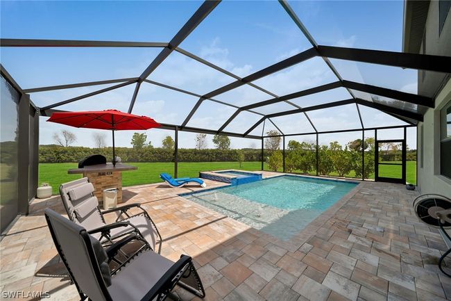 View of swimming pool featuring a patio area, an in ground hot tub, a lawn, and glass enclosure | Image 24
