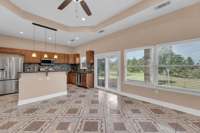 Kitchen with backsplash, appliances with stainless steel finishes, ceiling fan, light tile patterned floors, and brown cabinets | Image 10