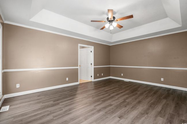 Unfurnished room featuring a tray ceiling, ceiling fan, wood finished floors, and crown molding | Image 18
