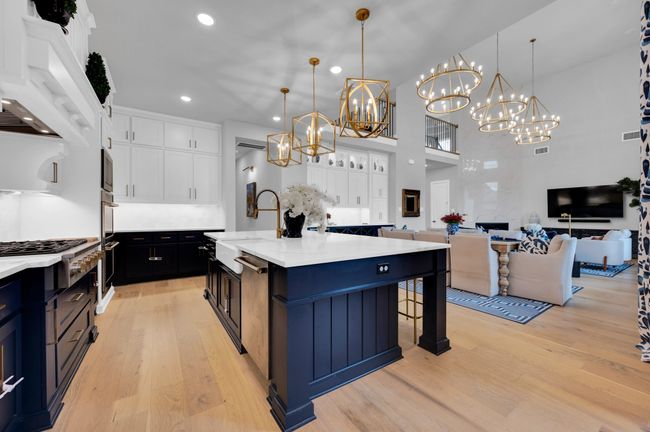 Kitchen with a chandelier, light wood finished floors, white cabinetry, recessed lighting, and stainless steel appliances | Image 17