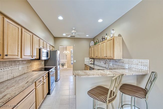 Kitchen featuring a kitchen breakfast bar, kitchen peninsula, stainless steel appliances, and light brown cabinetry | Image 24