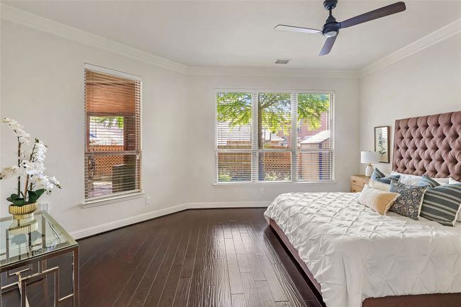 Bedroom with multiple windows, dark wood finished floors, crown molding, and ceiling fan | Image 13