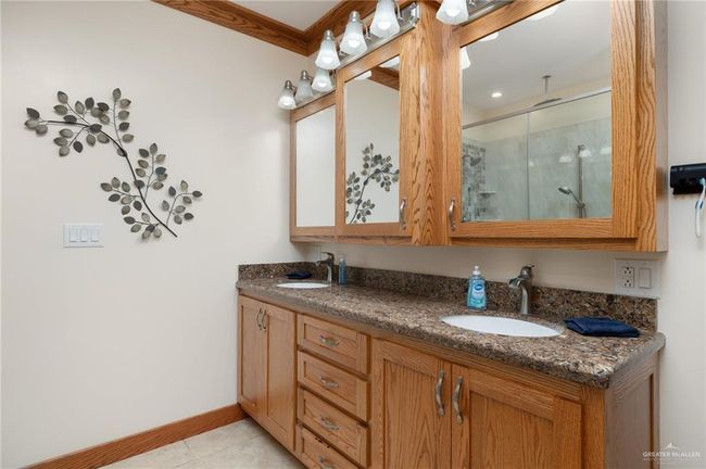 Bathroom featuring tile patterned flooring, vanity, a shower with door, and crown molding | Image 19